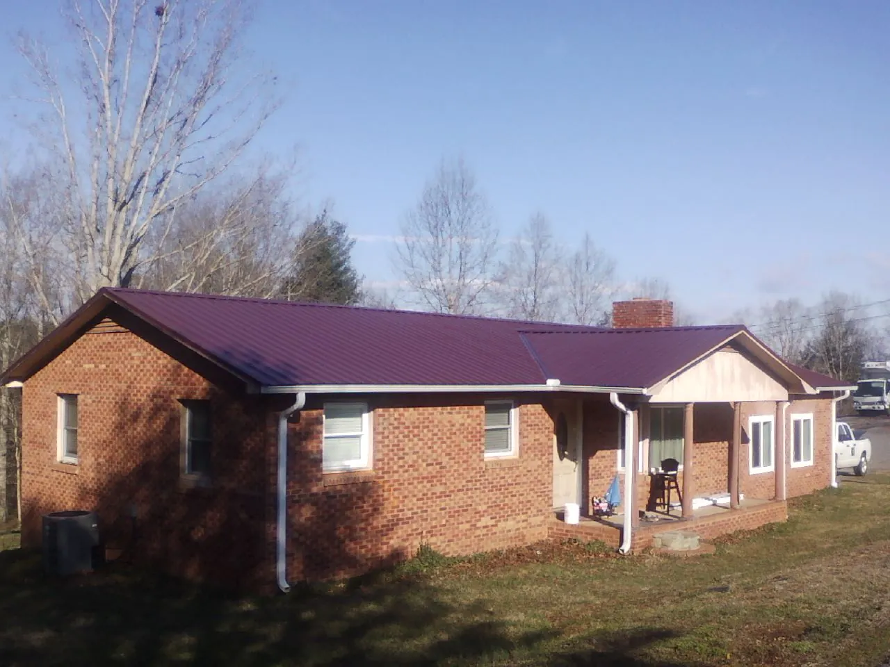 Burgundy metal roof on a brick ranch home with a new addition in Stone Creek