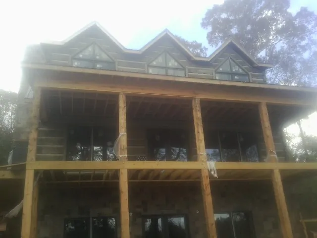 Dormers and porch framing on a large log home under construction — Roof Coating work by our crew in Stone Creek