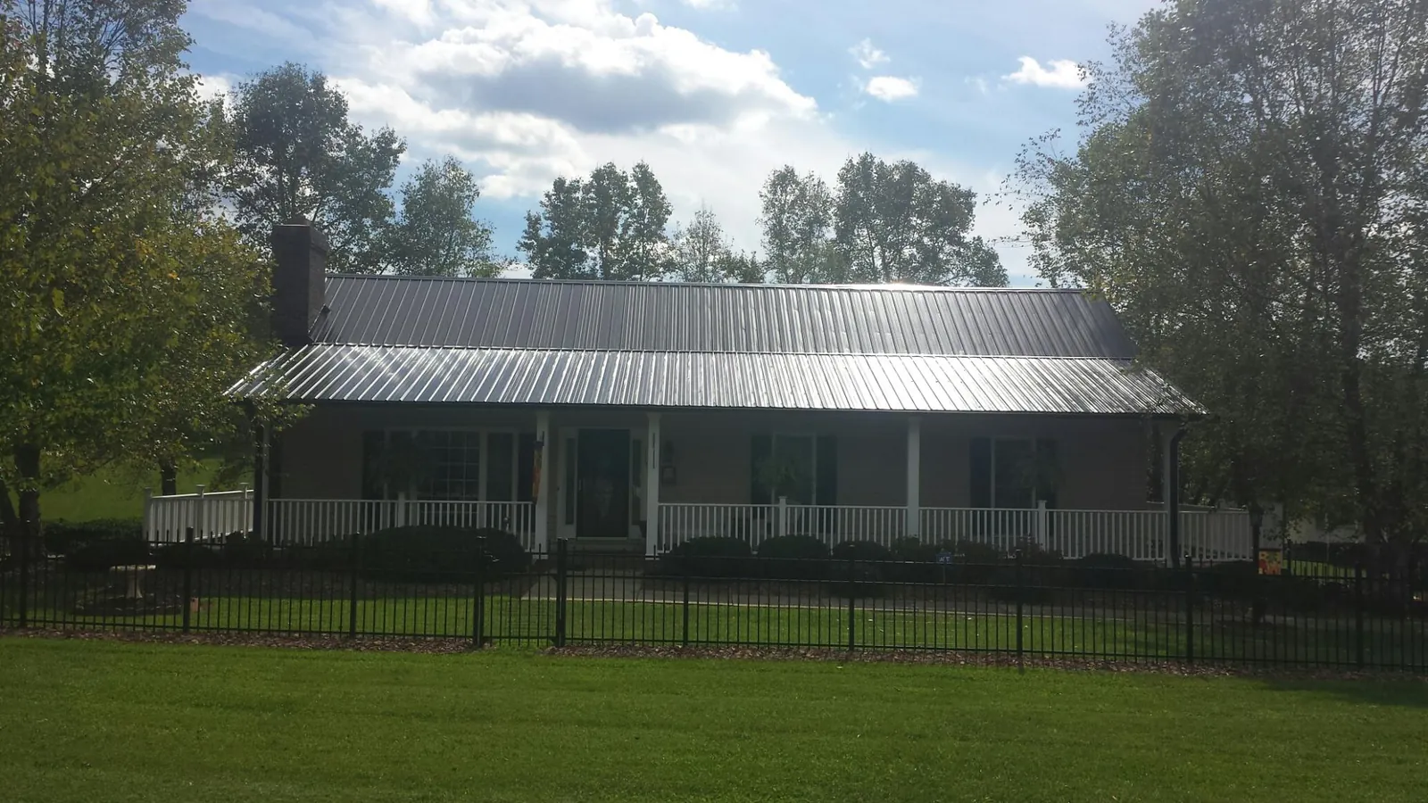 Gray metal roof on a brick ranch with a full width front porch — Gutter Guard Installation work by our crew in Stone Creek