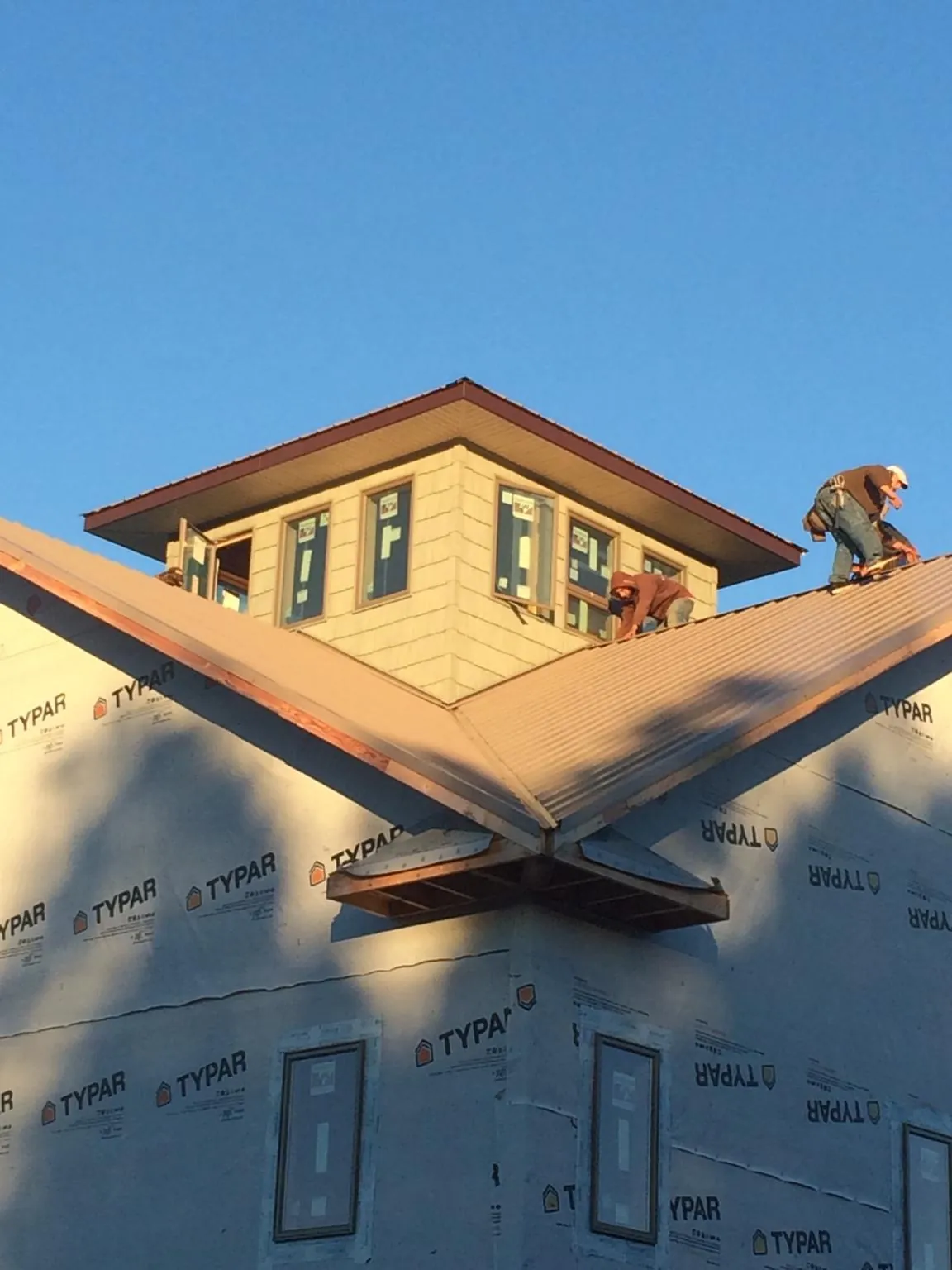 Roofers working around a rooftop cupola on a new metal roof at sunset — Roof Waterproofing in Stone Creek by Roofing Brothers